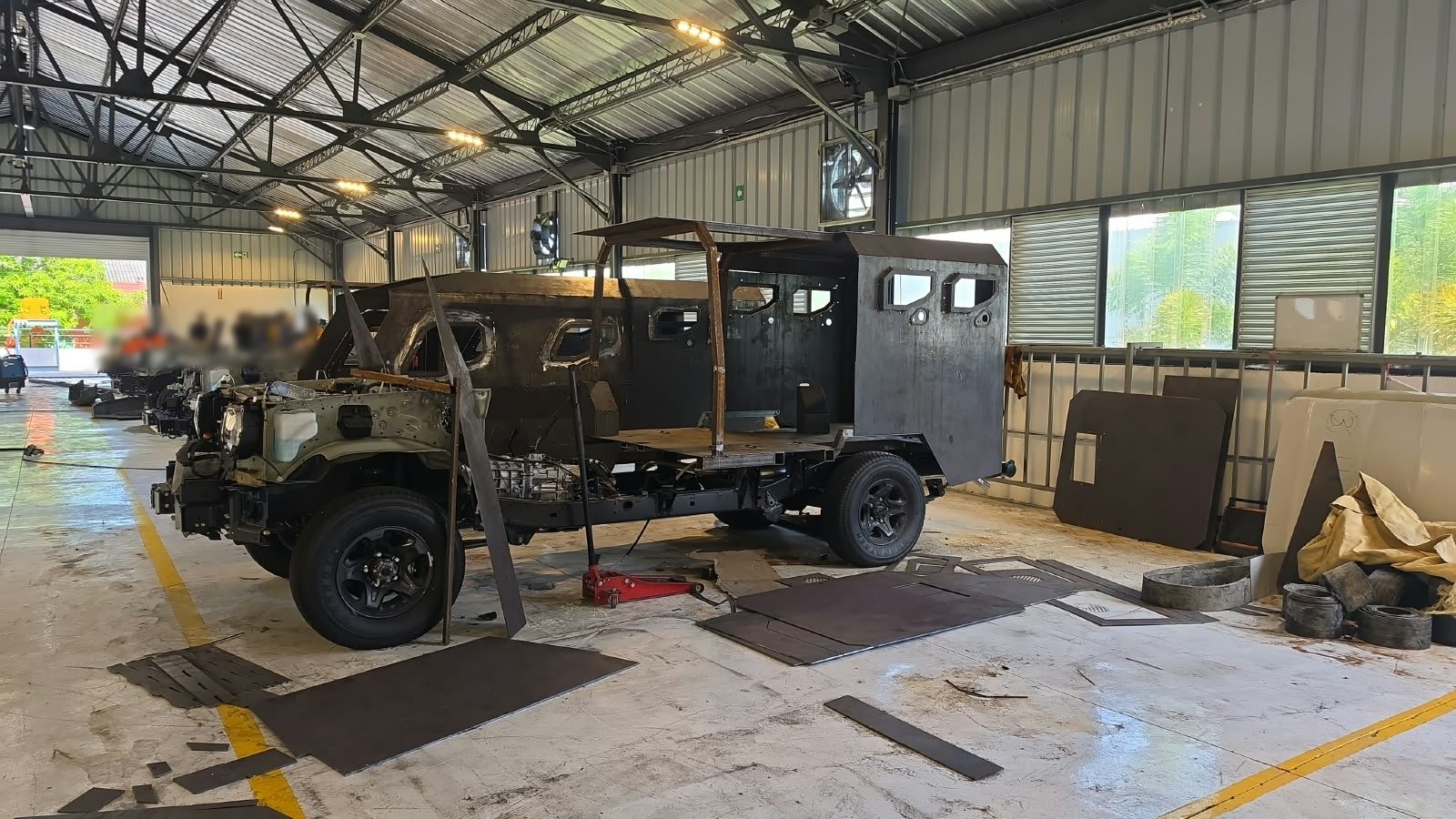 Chasis de un vehículo en ensamble dentro de una nave industrial, con operarios al fondo