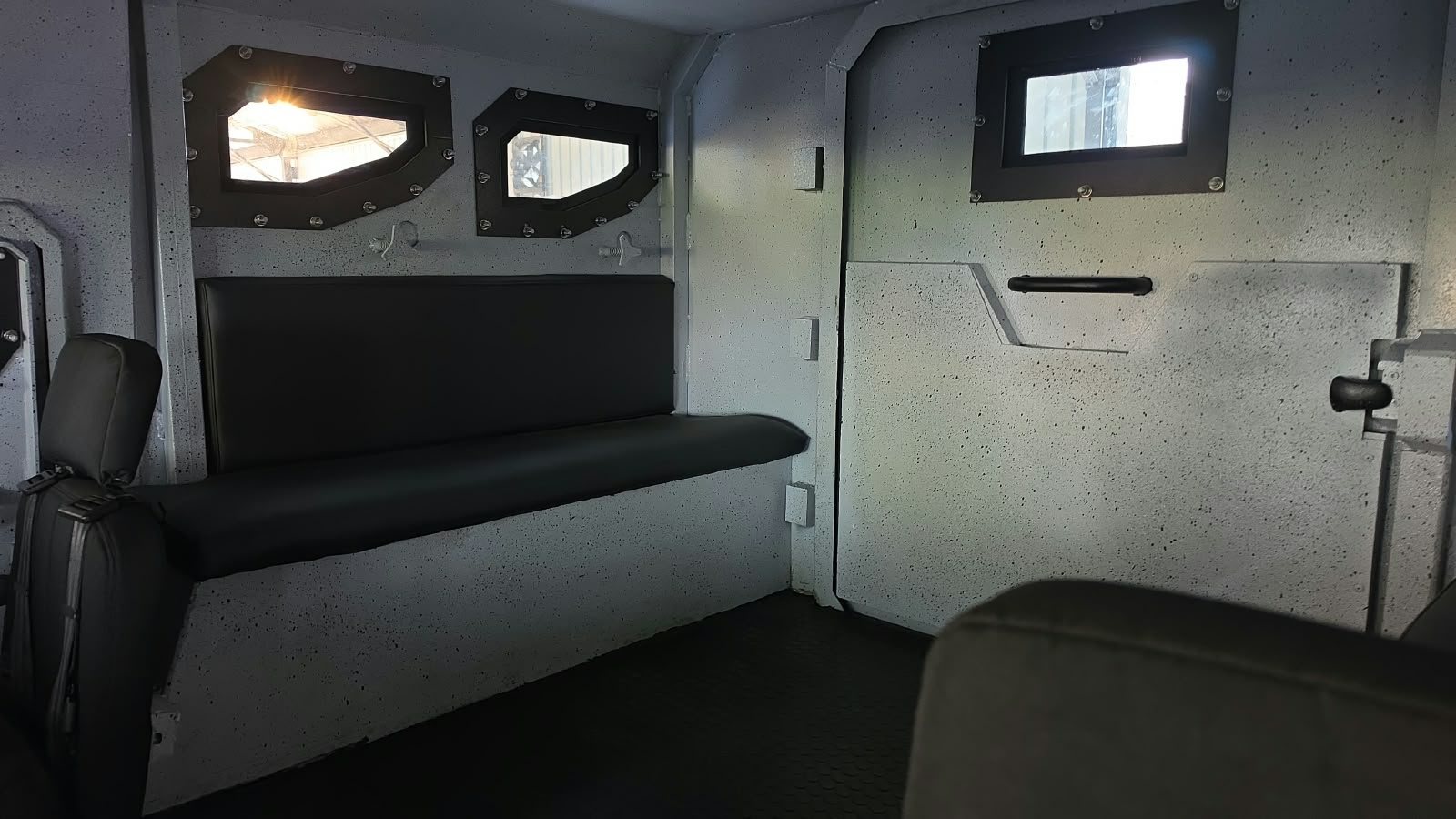 Interior blindado con banca tapizada y ventanas blindadas de bordes reforzados integradas en la carrocería