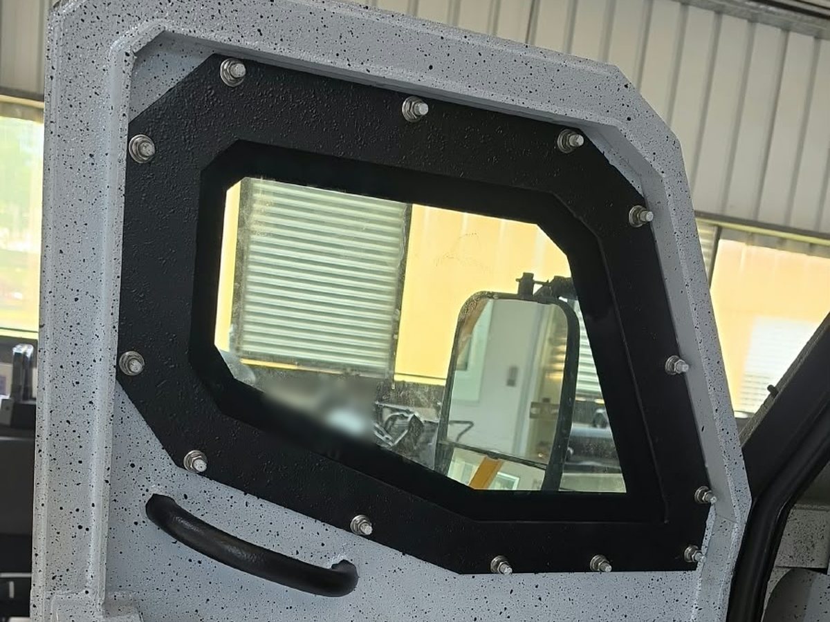 Ventana blindada de una puerta, con marco de acero reforzado y fijaciones atornilladas